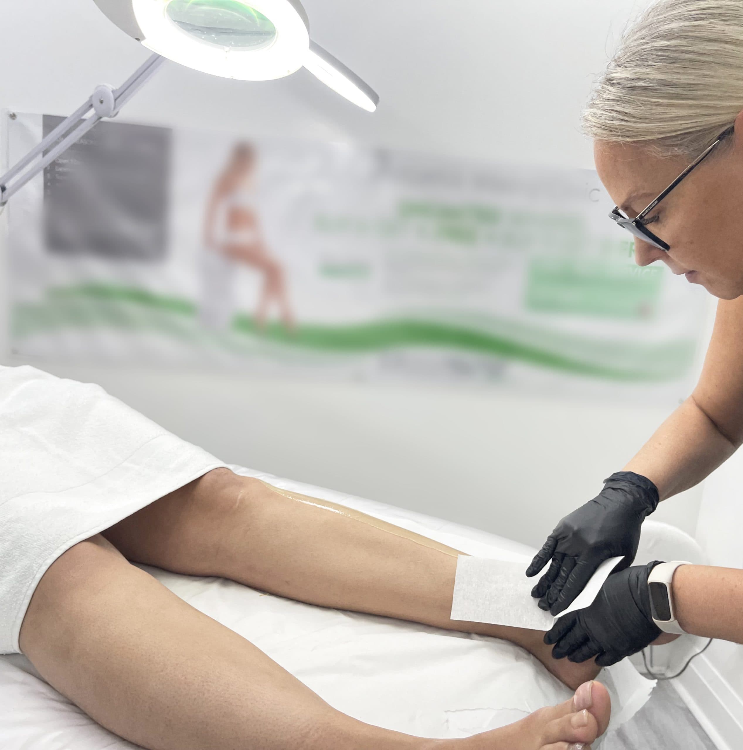 Waxologist pulling on a strip, for lower leg waxing