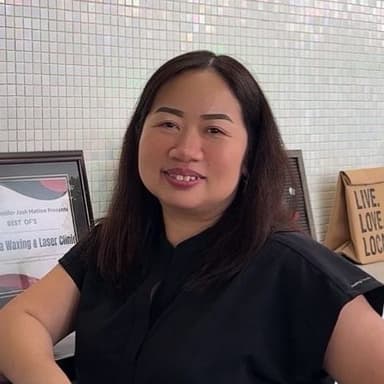 Dolores, exuding warmth and expertise, stands in her professional attire, symbolizing her dedication to waxing, sugaring, and threading services at Aroma Waxing Clinic